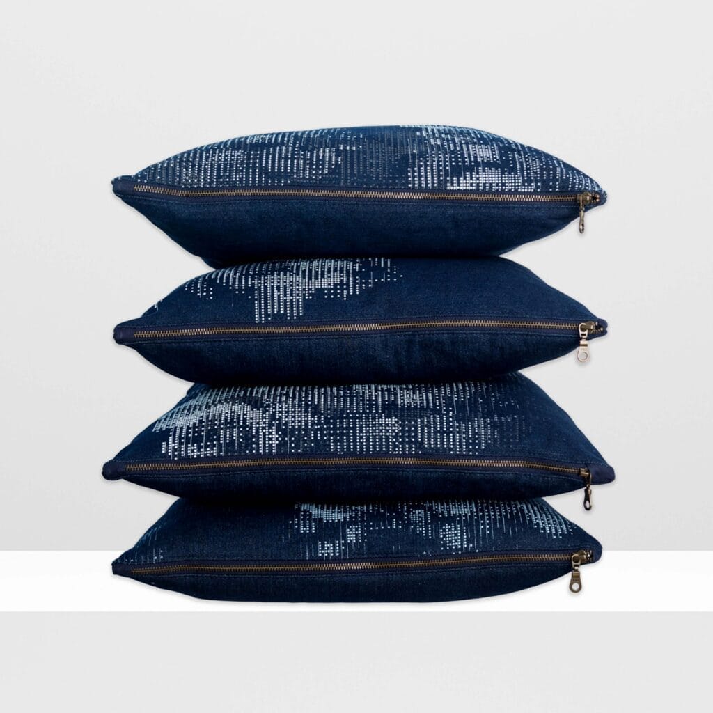 Stack of of Digital Moss large pillows by MIN-studio, screen-printed denim with layered abstract moss-like textures in blue, white, grey, and glow yellow inks.